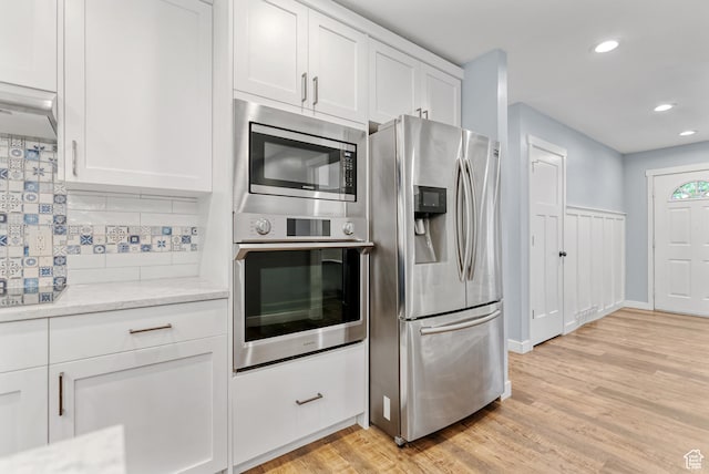kitchen with stainless steel appliances, light wood-type flooring, white cabinetry, recessed lighting, and backsplash