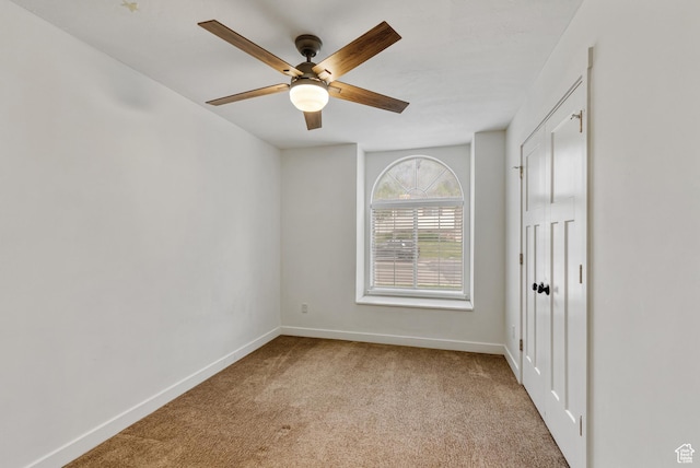 empty room featuring carpet, baseboards, and ceiling fan