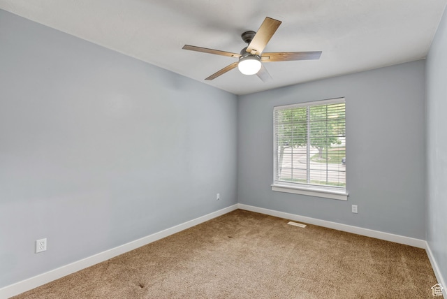 carpeted spare room with a ceiling fan and baseboards