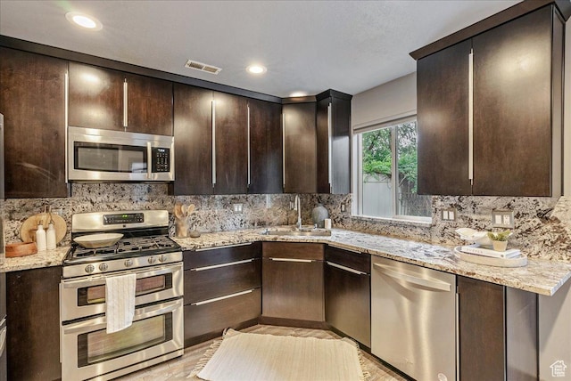 59 W 600 N, Farmington, UT 84025 - kitchen with stainless steel appliances, a sink, dark brown cabinetry, tasteful backsplash, and light stone countertops