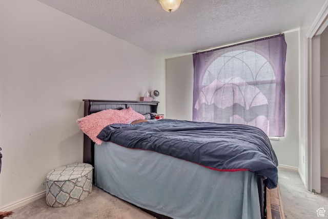 carpeted bedroom featuring a textured ceiling and baseboards