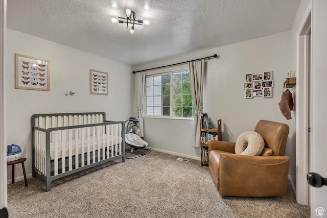 carpeted bedroom featuring a textured ceiling, a nursery area, and baseboards