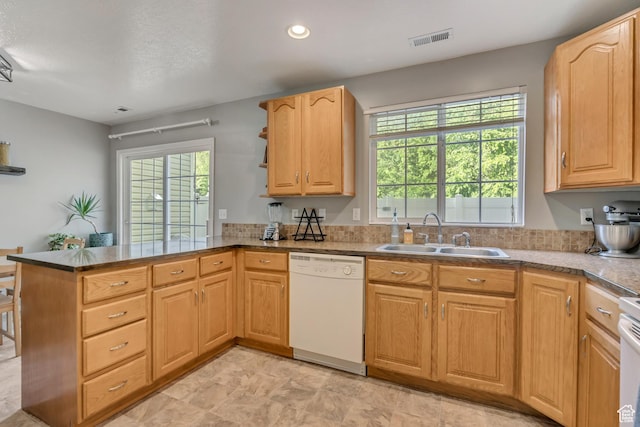 kitchen featuring dishwasher, a sink, a peninsula, plenty of natural light, and recessed lighting
