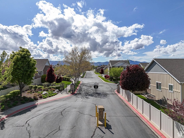 3263 W Blue Moon Ln, South Jordan, UT 84095 - view of asphalt road with a residential view, curbs, a gated entry, sidewalks, and a gate