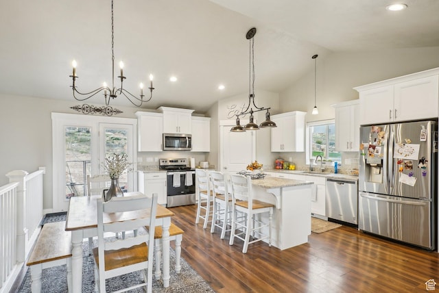 kitchen with appliances with stainless steel finishes, a sink, a kitchen island, a kitchen bar, and white cabinets