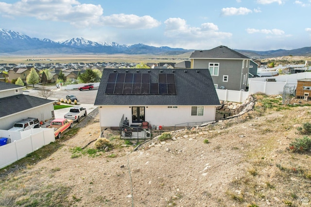 back of house with french doors, roof mounted solar panels, a fenced backyard, and a mountain view