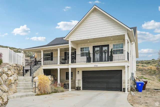 view of front facade with an attached garage, stairs, driveway, stone siding, and a porch
