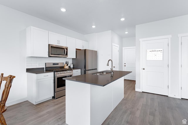 876 S Brubaker Way, Santaquin, UT 84655 - kitchen with appliances with stainless steel finishes, a sink, dark countertops, light wood-style floors, and a center island with sink