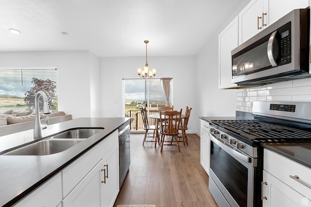 876 S Brubaker Way, Santaquin, UT 84655 - kitchen featuring appliances with stainless steel finishes, a sink, light wood finished floors, tasteful backsplash, and a chandelier