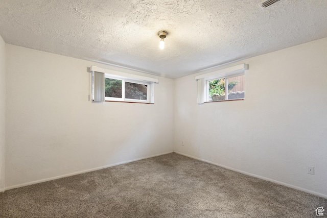 empty room featuring carpet, a textured ceiling, and baseboards