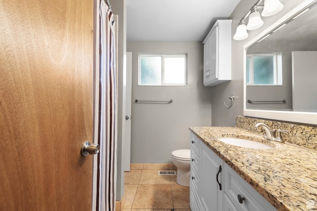 bathroom featuring toilet, plenty of natural light, vanity, and baseboards