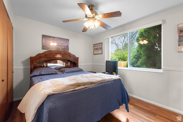 bedroom with wood finished floors, baseboards, and ceiling fan