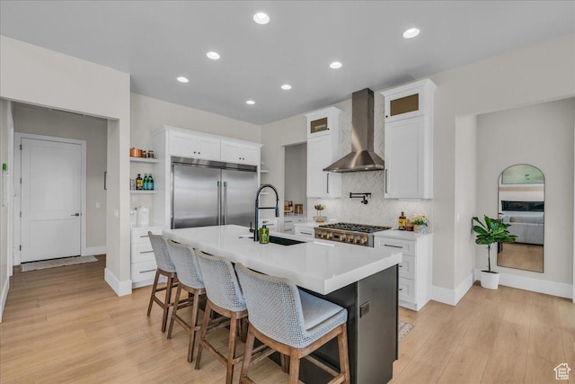 1003 N Grand Heights Dr, St George, UT 84770 - kitchen with wall chimney range hood, stainless steel appliances, a sink, light wood-style floors, and decorative backsplash