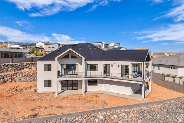 1003 N Grand Heights Dr, St George, UT 84770 - back of house with a balcony, stucco siding, metal roof, a patio, and fence