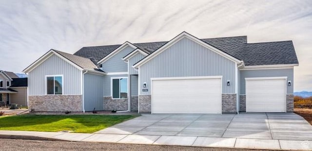 craftsman house featuring an attached garage, driveway, stone siding, and a front yard