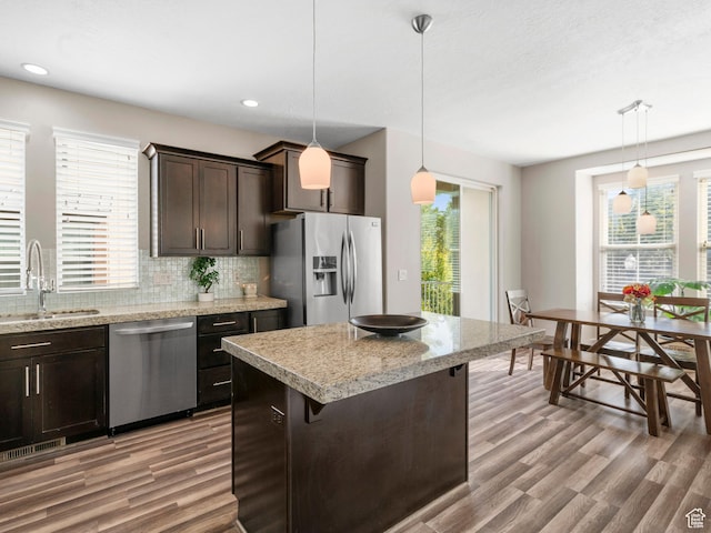 kitchen featuring stainless steel appliances, a sink, dark brown cabinets, light wood finished floors, and recessed lighting