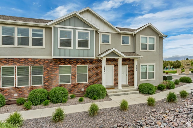 townhome / multi-family property featuring board and batten siding, stucco siding, and brick siding
