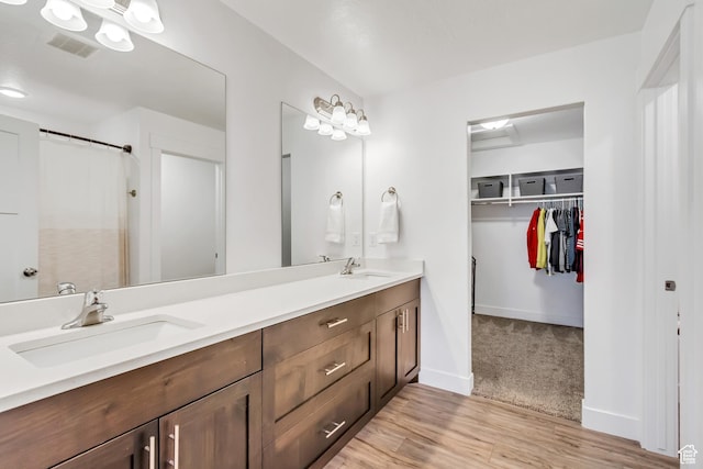 full bathroom with double vanity, a walk in closet, wood finished floors, and curtained shower
