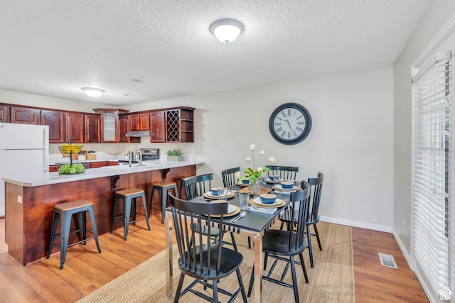 1140 E Elgin Ave S, Millcreek, UT 84106 - dining area featuring light wood-type flooring, a textured ceiling, and baseboards