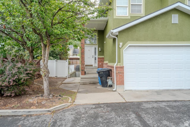 1140 E Elgin Ave S, Millcreek, UT 84106 - view of front of house with stucco siding, driveway, a garage, brick siding, and fence