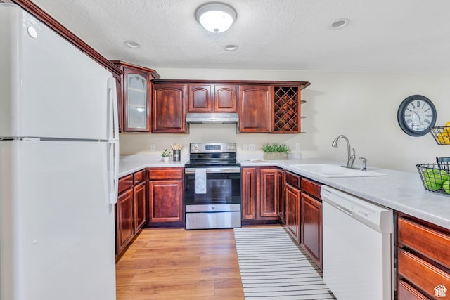 1140 E Elgin Ave S, Millcreek, UT 84106 - kitchen with white appliances, a sink, under cabinet range hood, dark brown cabinets, and light countertops