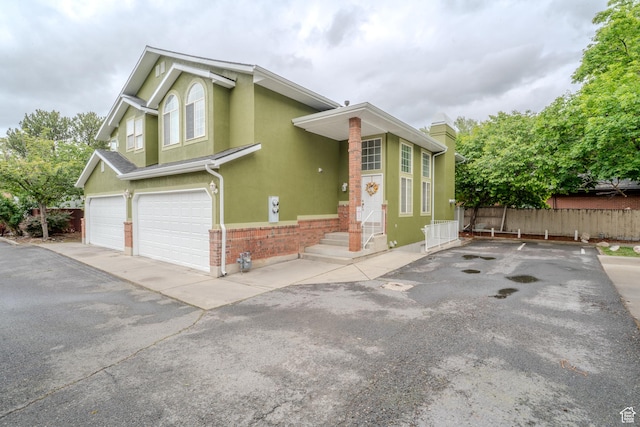 1140 E Elgin Ave S, Millcreek, UT 84106 - view of front facade featuring an attached garage, fence, driveway, stucco siding, and brick siding