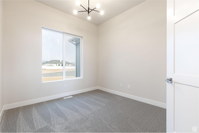 carpeted empty room featuring a chandelier and baseboards