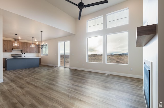 unfurnished living room with a ceiling fan, a sink, baseboards, wood finished floors, and a fireplace