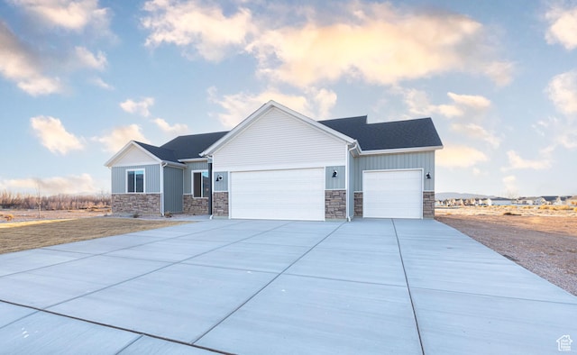 view of front of property with stone siding, an attached garage, driveway, and board and batten siding