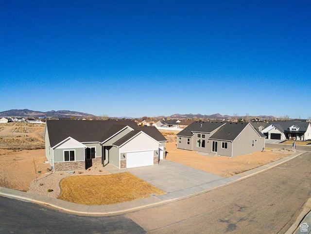 view of front of home with a residential view, asphalt driveway, a mountain view, and a garage