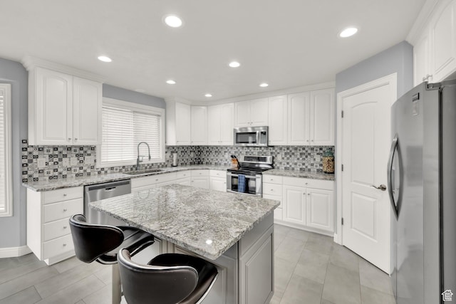 kitchen with stainless steel appliances, a sink, tasteful backsplash, white cabinets, and recessed lighting