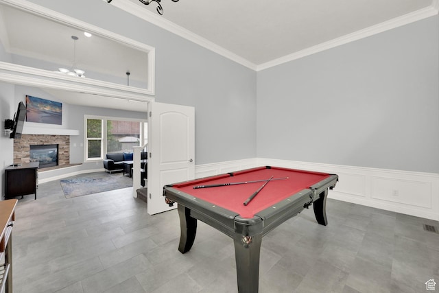 playroom featuring crown molding, wainscoting, billiards table, and a stone fireplace