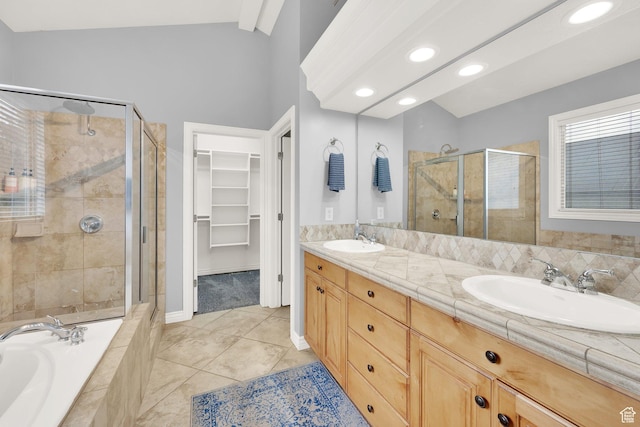 bathroom featuring a stall shower, a spacious closet, double vanity, a bath, and vaulted ceiling