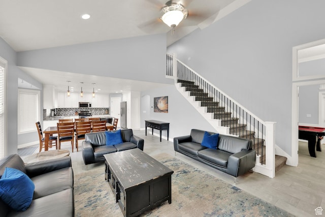 living area with stairs, a ceiling fan, recessed lighting, high vaulted ceiling, and baseboards