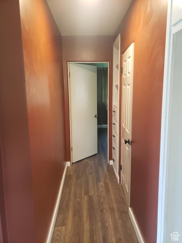 hallway featuring dark wood-style floors and baseboards