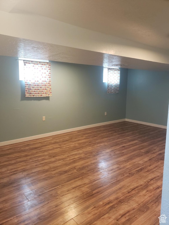 below grade area featuring wood finished floors, baseboards, and healthy amount of natural light