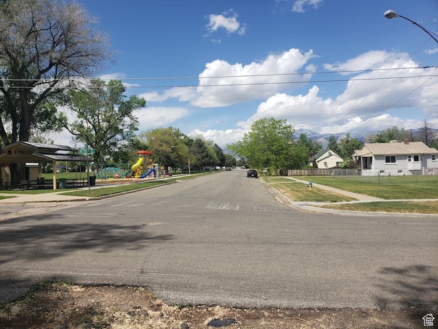 view of asphalt street featuring sidewalks, street lights, and curbs