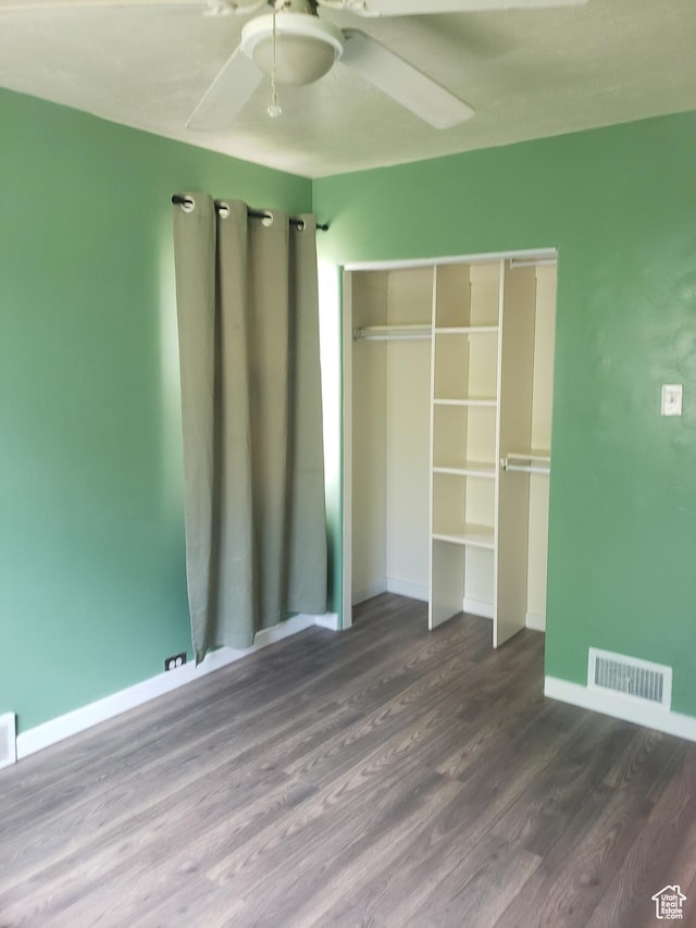 unfurnished bedroom with wood finished floors, baseboards, a closet, and a ceiling fan