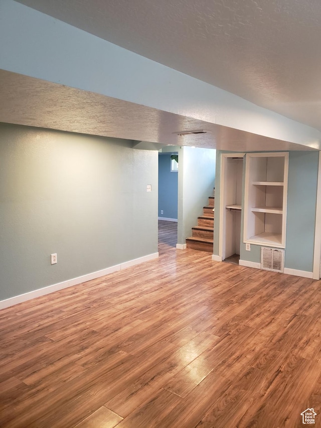 finished below grade area with wood finished floors, baseboards, stairway, and built in features