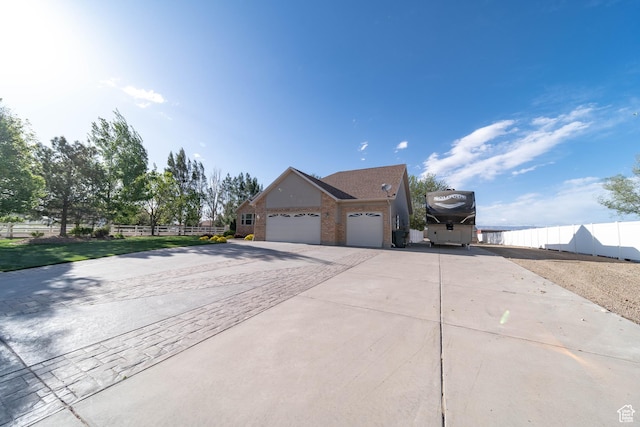 view of property exterior with driveway, an attached garage, brick siding, and fence