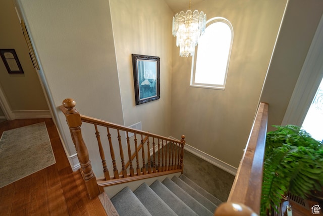 stairway featuring healthy amount of natural light, a chandelier, and baseboards