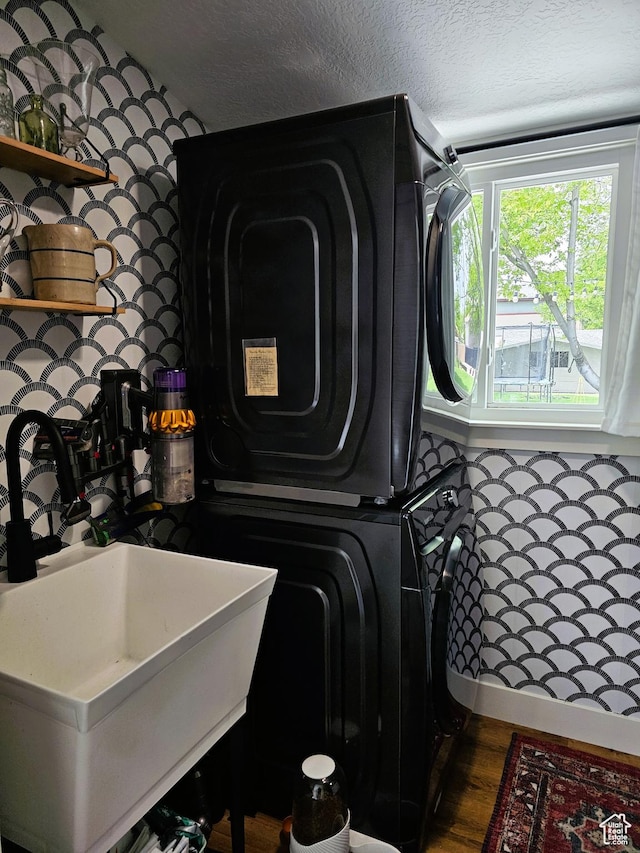 44 S 700 E, Provo, UT 84606 - clothes washing area featuring stacked washer and clothes dryer, a sink, a textured ceiling, and dark wood-type flooring