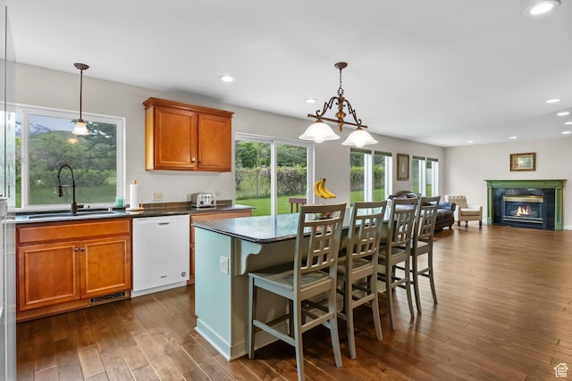 kitchen featuring dishwasher, a sink, dark wood-type flooring, a glass covered fireplace, and brown cabinets