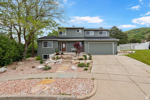 traditional-style house featuring fence, concrete driveway, a garage, a porch, and a mountain view
