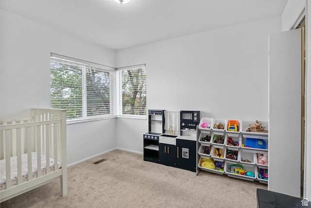 bedroom with carpet floors, a crib, and baseboards