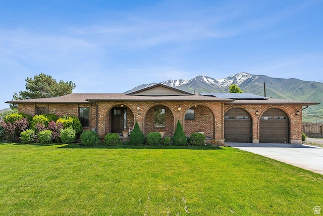 view of front of property with a mountain view, a garage, solar panels, concrete driveway, and brick siding