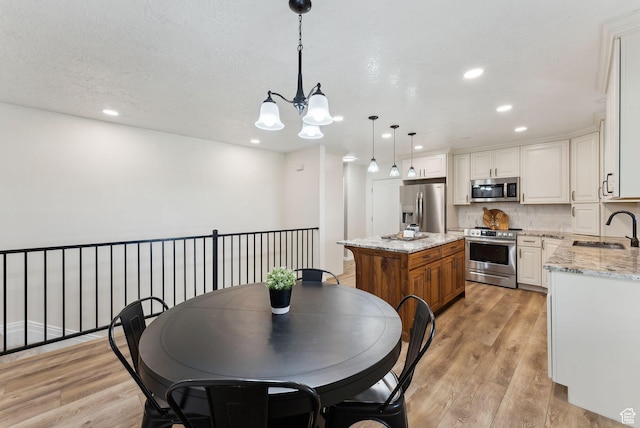 dining space featuring a chandelier, light wood-style floors, and recessed lighting
