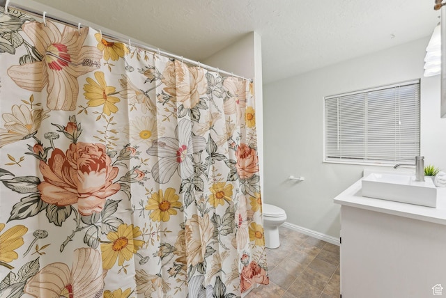 bathroom with toilet, baseboards, vanity, and a textured ceiling