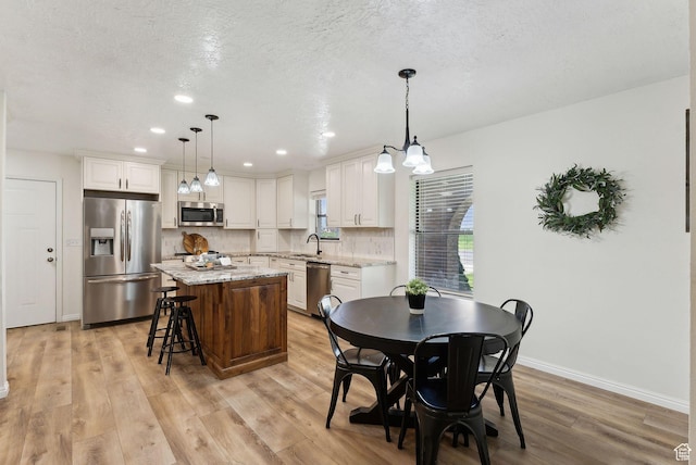 dining space featuring light wood-type flooring, baseboards, recessed lighting, and a textured ceiling