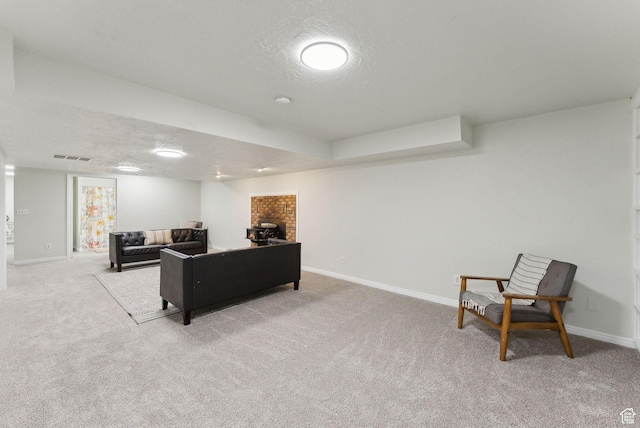 carpeted living room featuring baseboards, a textured ceiling, and a brick fireplace